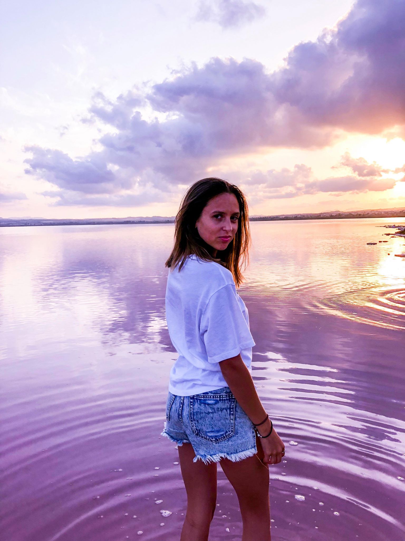 girl looking back with radiant pink waters and pink sky in torrevieja spain