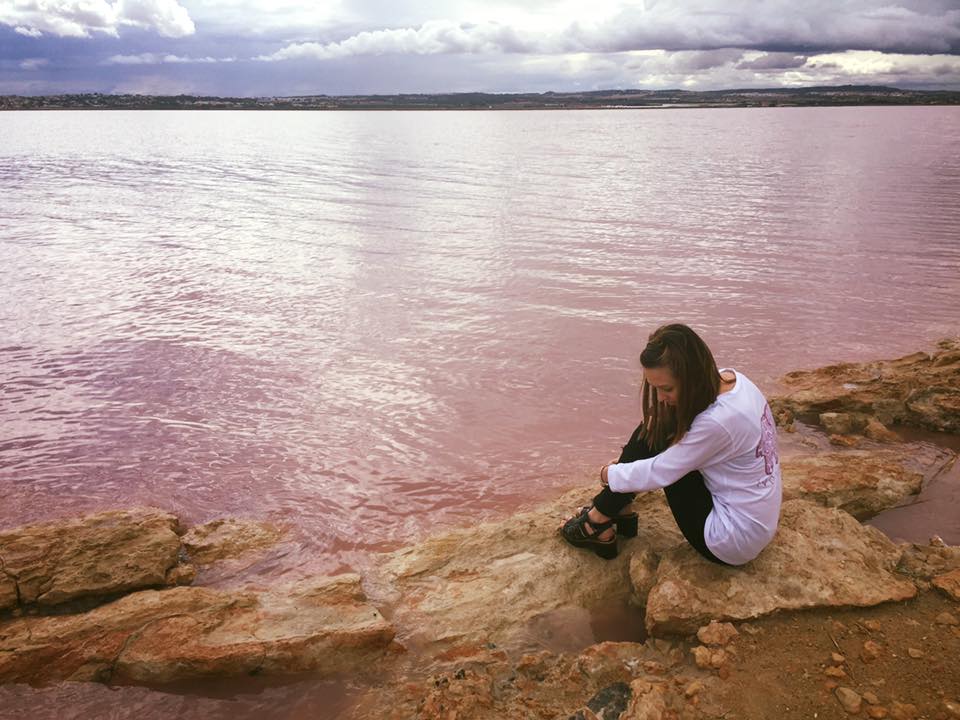 sitting on the pink water looking down at pink water and purple sky spain