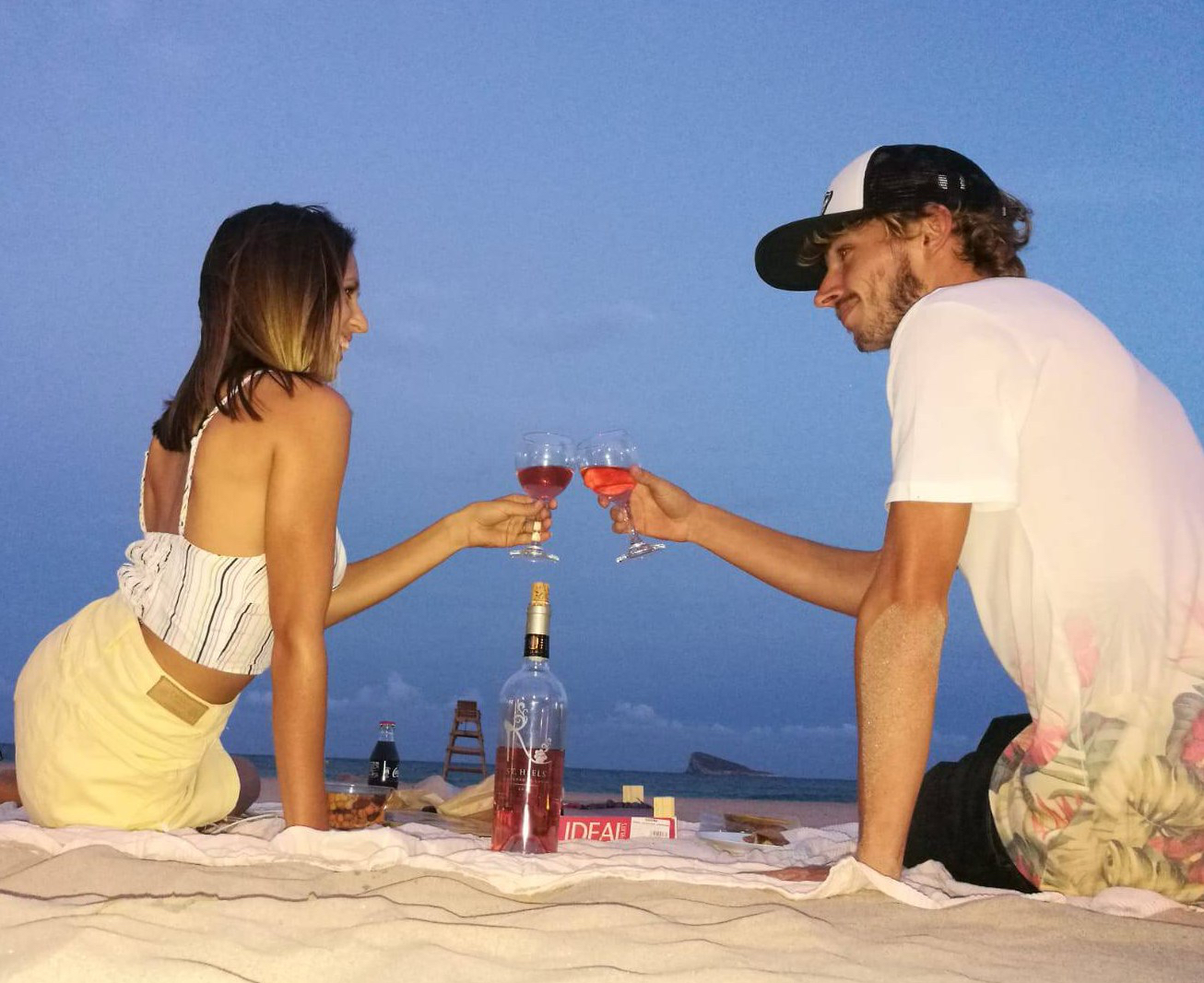 Beautiful beach picnic at night with a couple drinking wine