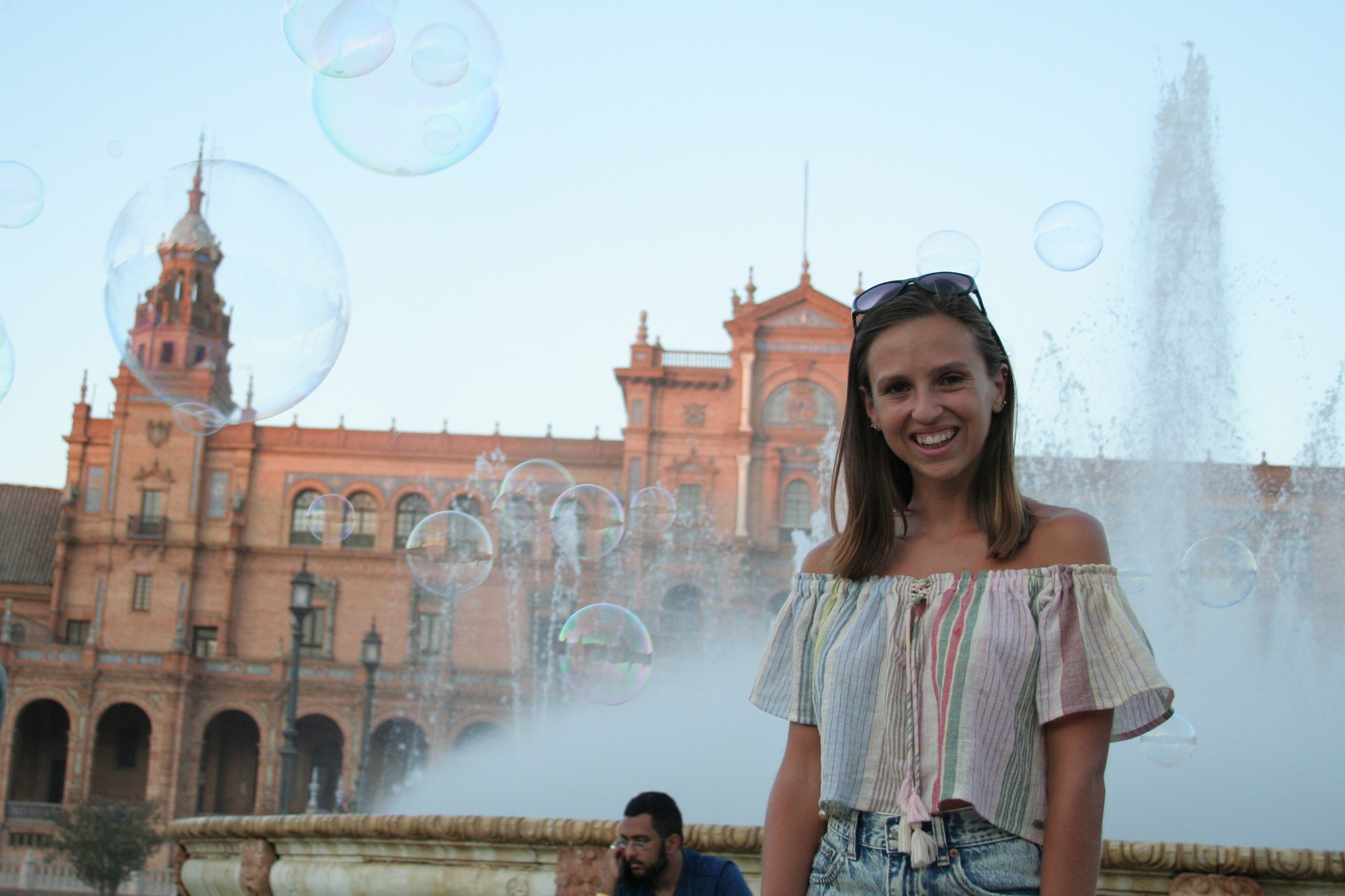 girl smiling with bubbles and fountain behind at maria luisa park plaza de espana