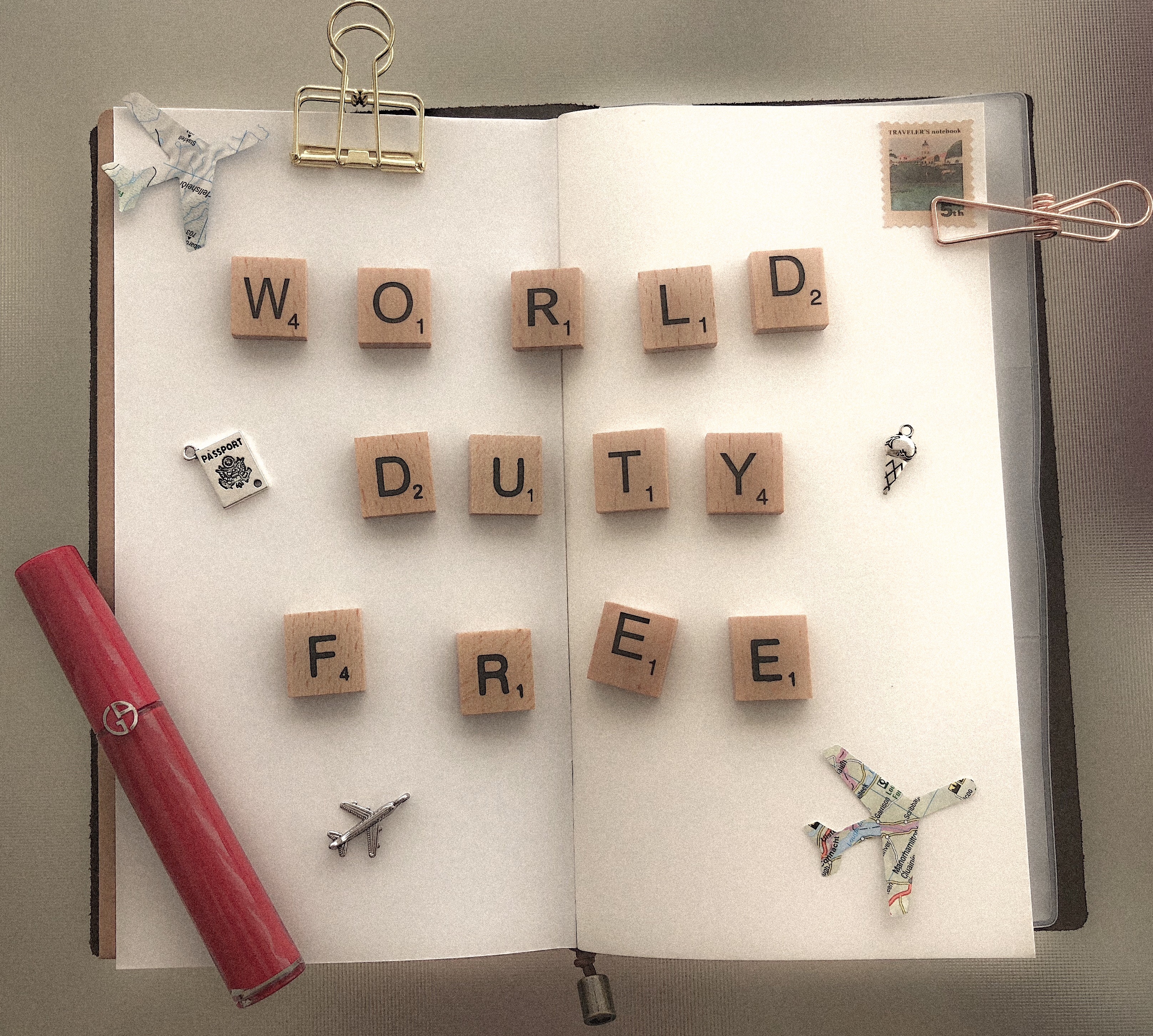 open nomad traveller book with the words world duty free with airplanes and giorgio armani lip colour