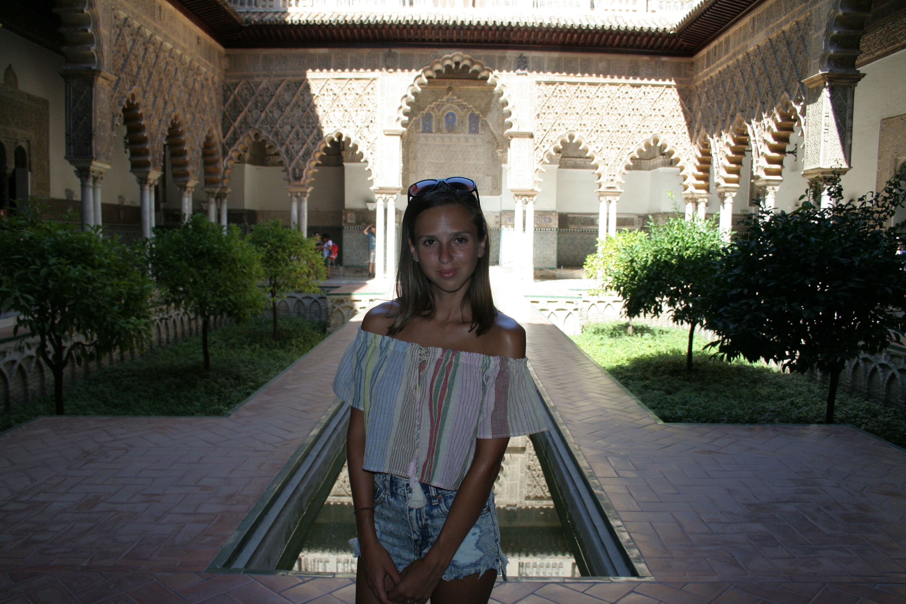 girl smiling with the sun reflecting behind in alcazar seville