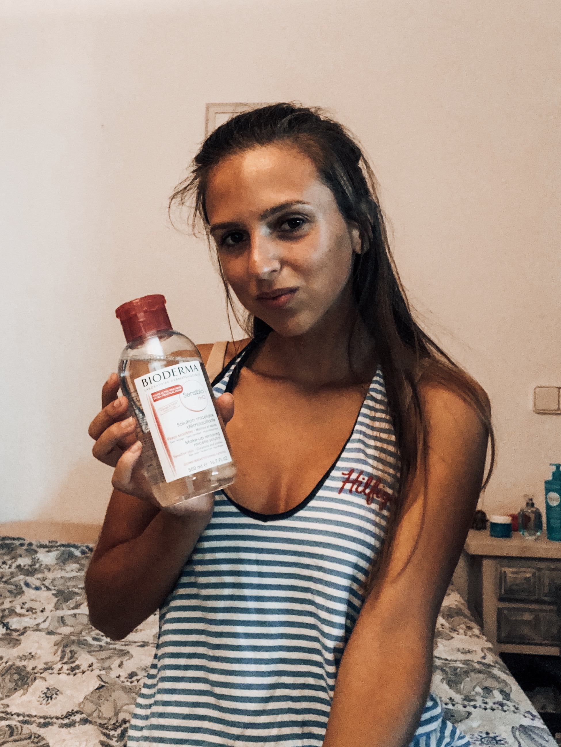 girl holding micellar water in bed bioderma