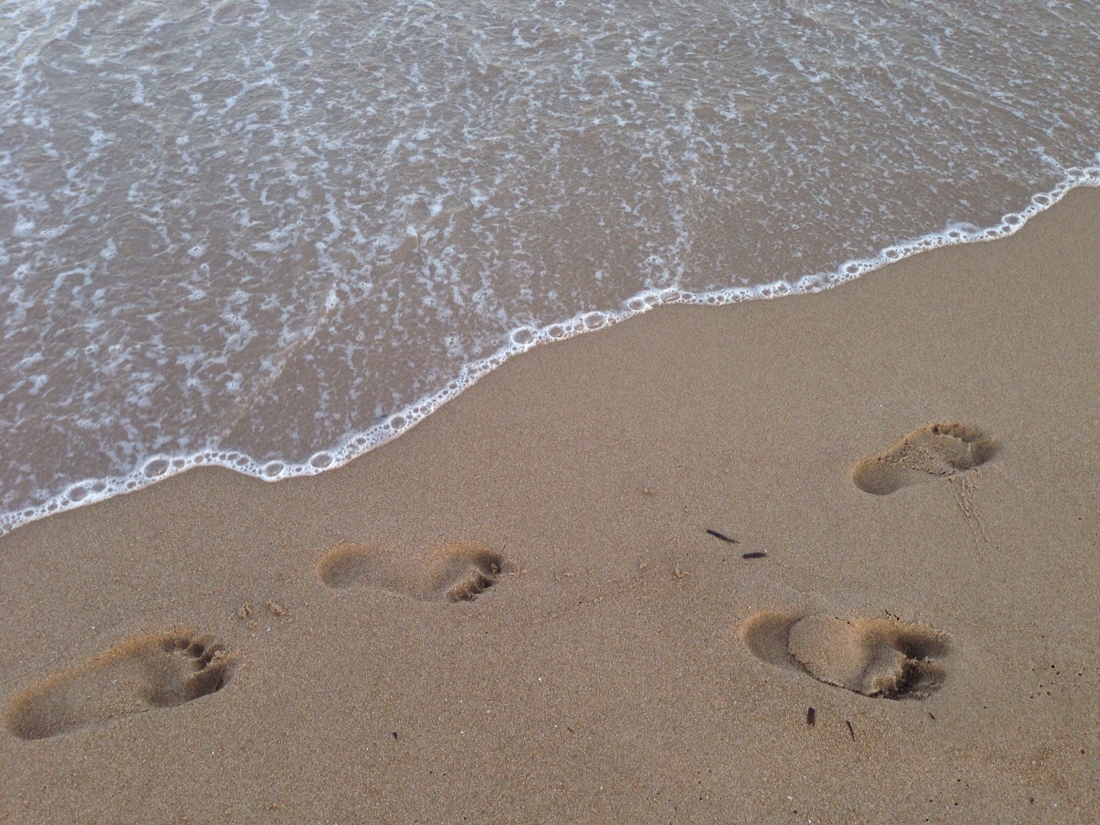 four footprints in the sand of levante beach with the shoreline