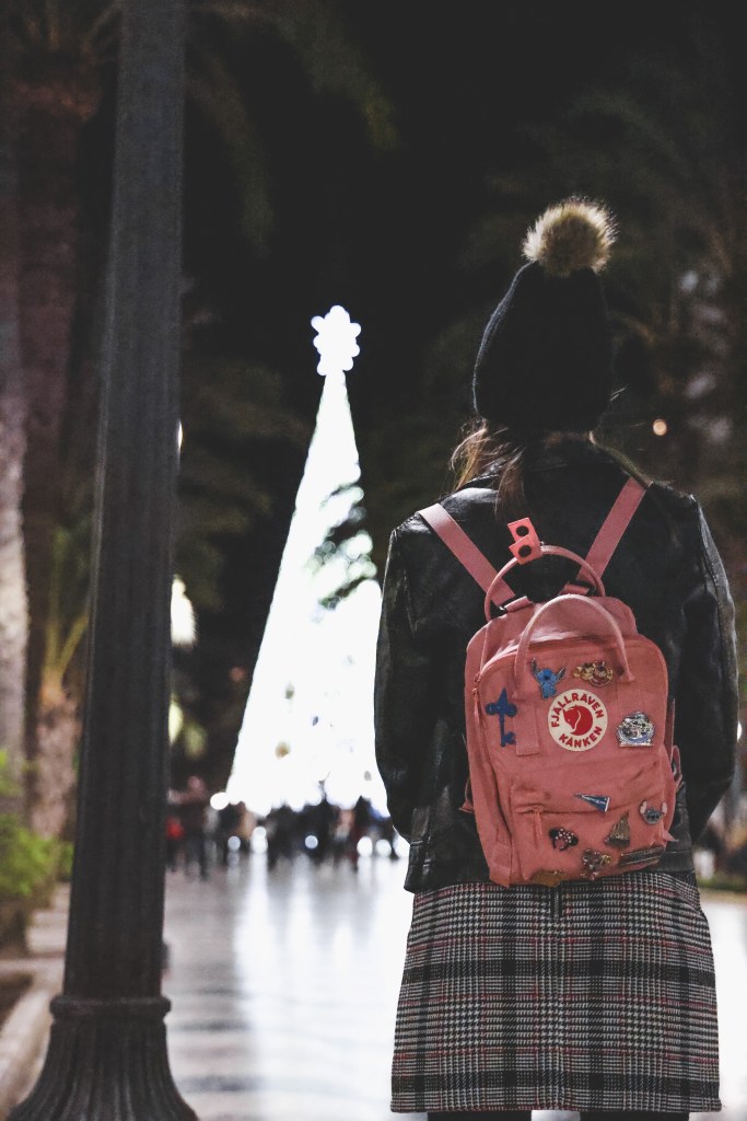 Girl standing facing Christmas tree back to camera 